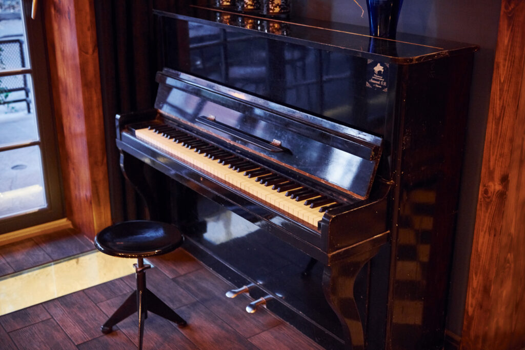Warum Talent für das Erlernen eines Instruments nicht ausschlaggebend ist Klavier mit Klavierhocker in einer Zimmerecke